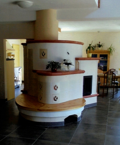 Kachelrundofen mit Holzsitzbank und roten Kacheln