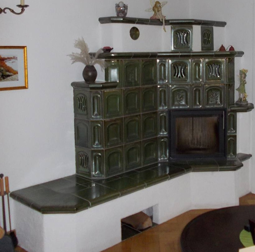 Warmluft-Speicherofen mit grünen Kacheln und Sitzbank