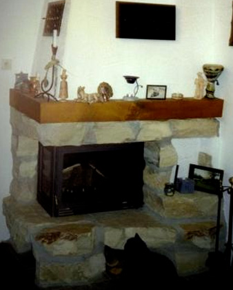 Eck-Kamin mit groben Natursteinen und Holzsims