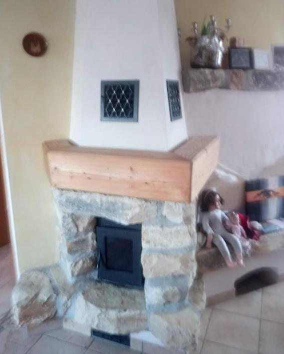 Natursteinkamin mit Holzsims und Metallüftungsfenstern